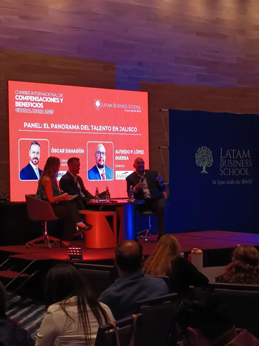Panel de tres participantes en el escenario de una Cumbre C&B